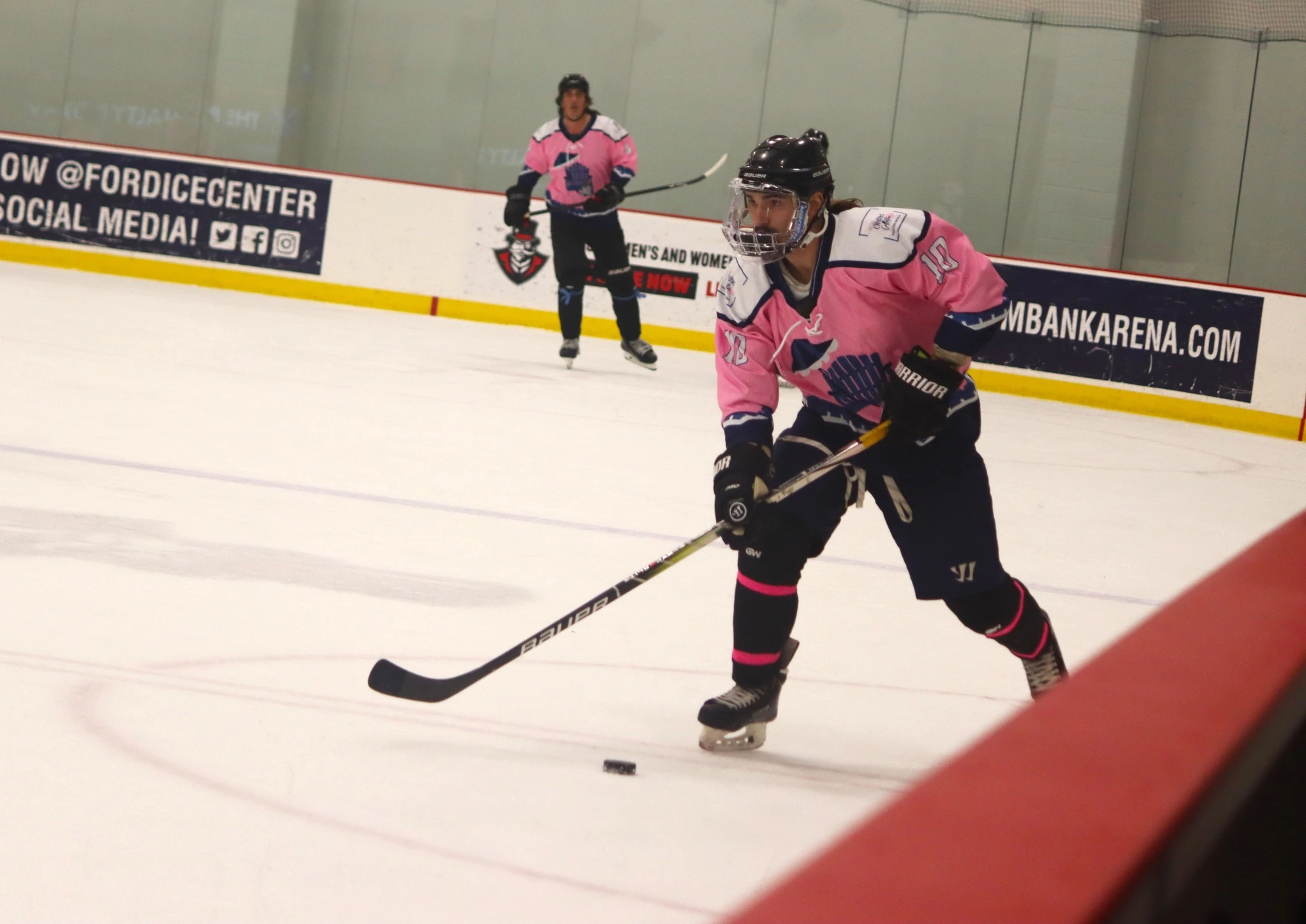 Dalton Henderson in pink jersey skating with the puck.